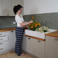 Woman wearing blue tartan plaid flannel short length pyjama bottoms in kitchen