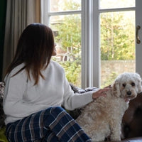 Woman wearing blue tartan plaid flannel short length pyjama bottoms in living room