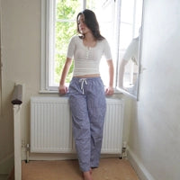 Woman wearing navy blue tartan gingham short length pyjama bottoms in living room