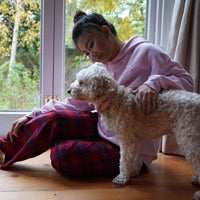 Woman wearing blue tartan plaid flannel short length pyjama bottoms in living room